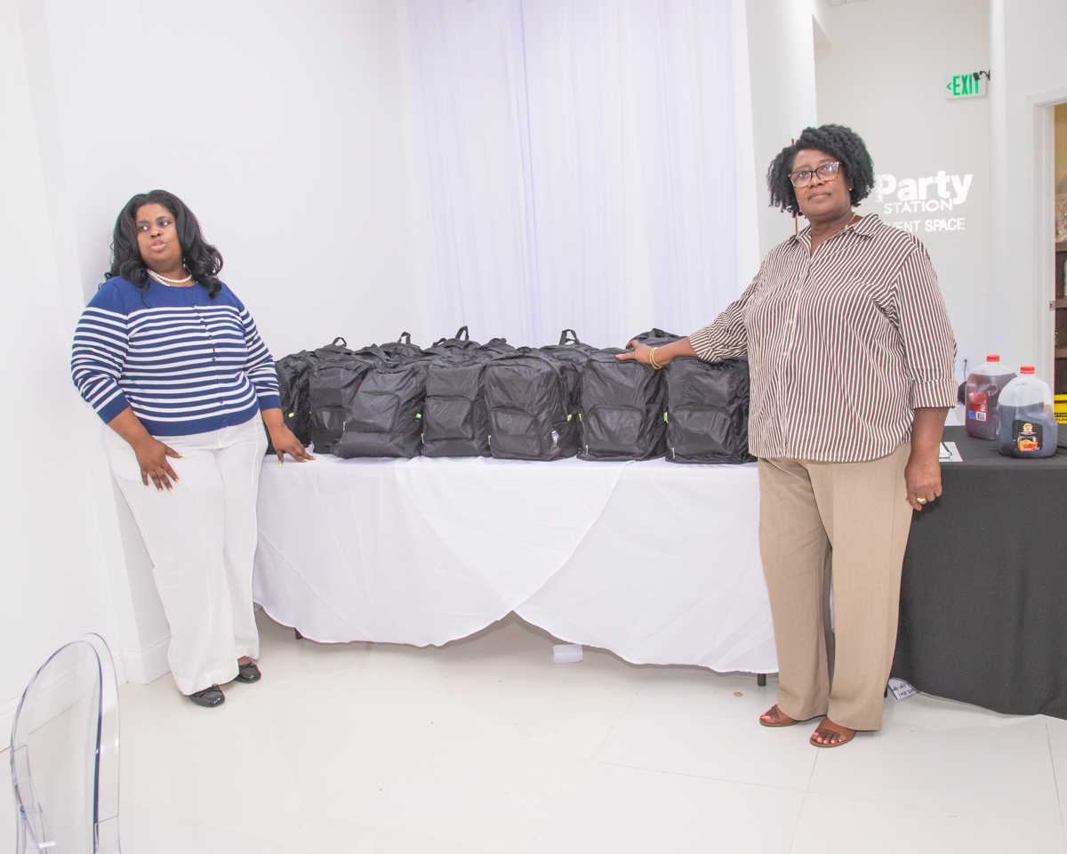 Volunteers standing beside a table of emergency preparedness backpacks